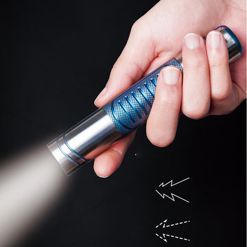 Hand holding a blue flashlight against a black background